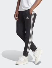 adidas Sportswear - ESSENTIALS FLEECE TAPERED CUFF 3-STRIPES PANTS - pants - black/white - 0